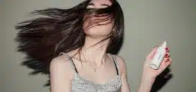 une femme mettant un spray dans ses cheveux